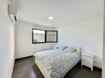 a white bedroom with a bed and a window at 2 pièces au cœur de la ville de Propriano in Propriano