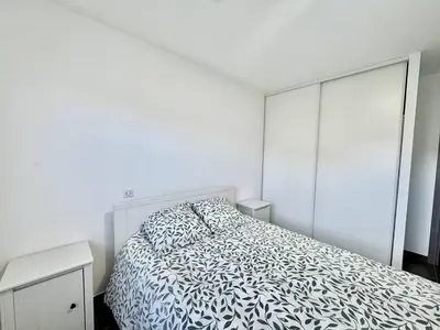 a bedroom with a bed with a black and white comforter at 2 pièces au cœur de la ville de Propriano in Propriano