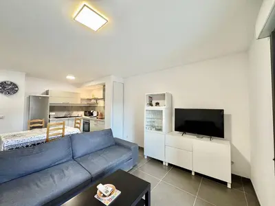 a living room with a blue couch and a flat screen tv at 2 pièces au cœur de la ville de Propriano in Propriano