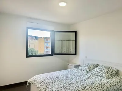 a white bedroom with a bed and a window at 2 pièces au cœur de la ville de Propriano in Propriano