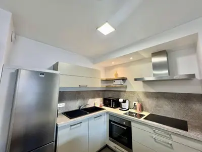 a kitchen with white cabinets and a stainless steel refrigerator at 2 pièces au cœur de la ville de Propriano in Propriano