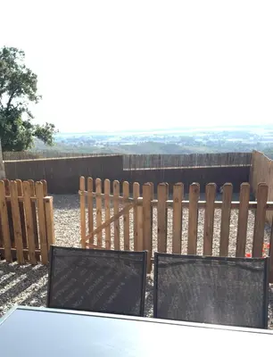 a wooden fence with three chairs in front of a table at Appartement vue mer et montagne in Olmeta-di-Tuda