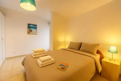 a bedroom with a large bed with towels on it at Mini villa vue jardin dans résidence calme wifi piscine mer à pied in Serra-di-Ferro