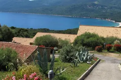 a house with a view of a body of water at Mini villa vue jardin dans résidence calme wifi piscine mer à pied in Serra-di-Ferro
