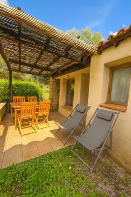 a patio with four chairs and a table and a wooden pergola at Mini villa vue jardin dans résidence calme wifi piscine mer à pied in Serra-di-Ferro