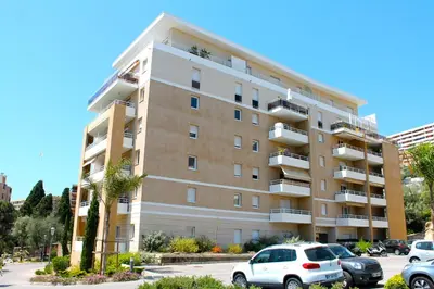 a large apartment building with cars parked in a parking lot at Appartement 3 étoiles près des plages d'Ajaccio in Ajaccio