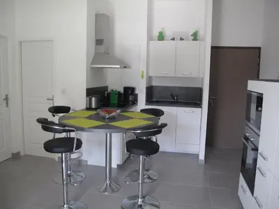 a small kitchen with a table and stools in it at Appartement 3 étoiles près des plages d'Ajaccio in Ajaccio