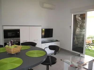 a dining room with a table and chairs and a kitchen at Appartement 3 étoiles près des plages d'Ajaccio in Ajaccio