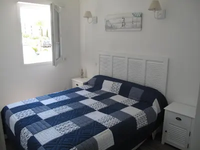 a bedroom with a blue and white bed with a window at Appartement 3 étoiles près des plages d'Ajaccio in Ajaccio