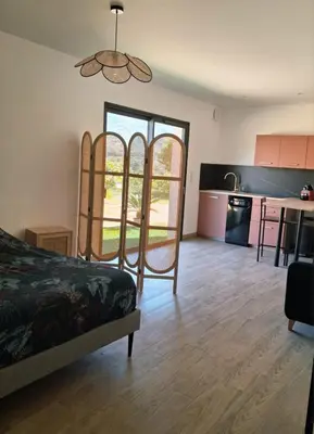 a living room with a bed and a kitchen at Lumineux studio entre terre et mer à 2min de la plage in Calcatoggio