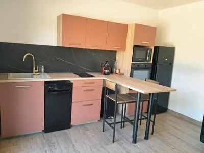 a kitchen with a wooden table and a counter top at Lumineux studio entre terre et mer à 2min de la plage in Calcatoggio