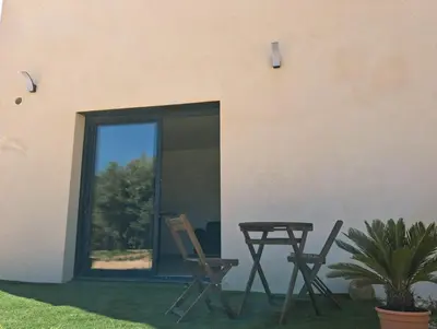 a patio with two chairs and a table next to a building at Lumineux studio entre terre et mer à 2min de la plage in Calcatoggio