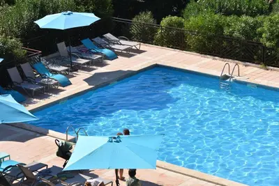 a large swimming pool with blue umbrellas and chairs at Ajaccio Sanguinaires - 3p - Terrasse - Piscine in Ajaccio