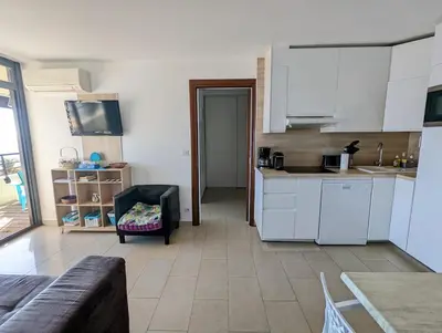 a kitchen with white cabinets and a couch in a room at Ajaccio Sanguinaires - 3p - Terrasse - Piscine in Ajaccio