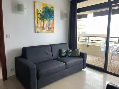 a black couch in a living room with a window at Ajaccio Sanguinaires - 3p - Terrasse - Piscine in Ajaccio