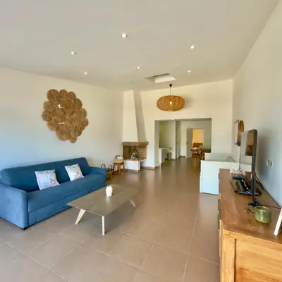 a living room with a blue couch and a table at Deux pièces tout confort vue mer imprenable in Propriano