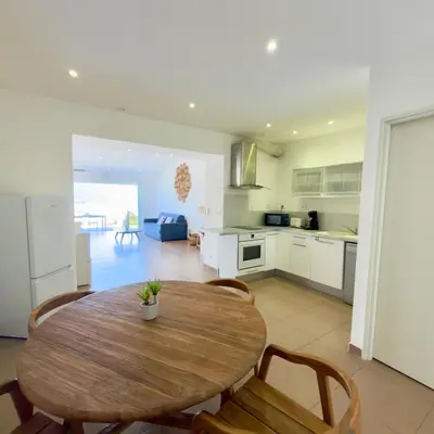 a kitchen with a table and a white refrigerator at Deux pièces tout confort vue mer imprenable in Propriano