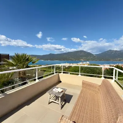 a balcony with a table and a view of the water at Deux pièces tout confort vue mer imprenable in Propriano