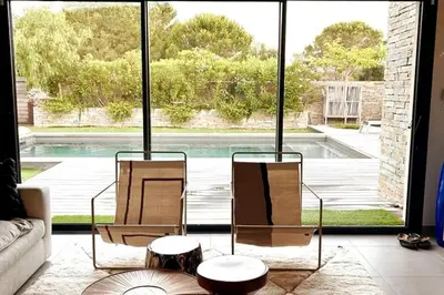 a living room with two chairs and a large window at Charming setting with private pool in Cala Rossa in Lecci