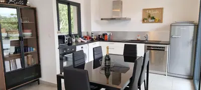 a kitchen with a counter with a table and a refrigerator at Godichard Apartment in a residence for 46 people with swimming pool and in Porto-Vecchio