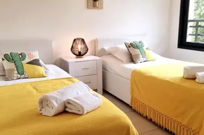 two beds in a room with yellow sheets at Godichard Apartment in a residence for 46 people with swimming pool and in Porto-Vecchio