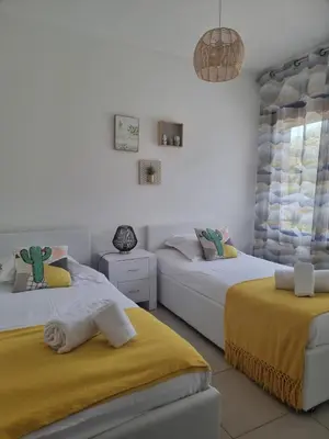 a bedroom with two beds with yellow sheets at Godichard Apartment in a residence for 46 people with swimming pool and in Porto-Vecchio