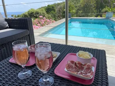 a table with two wine glasses and a tray of food at Villa with pool, sea view, Ste Lucie de Porto-Vecchio in Conca