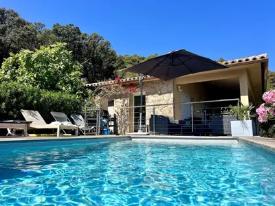a swimming pool with an umbrella next to a house at Villa with pool, sea view, Ste Lucie de Porto-Vecchio in Conca