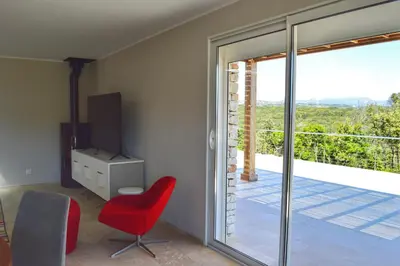 a living room with a red chair and a sliding glass door at Villa Serena - 10mn de la plage in Bonifacio