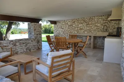 a patio with a table and chairs and a stone wall at Villa Serena - 10mn de la plage in Bonifacio