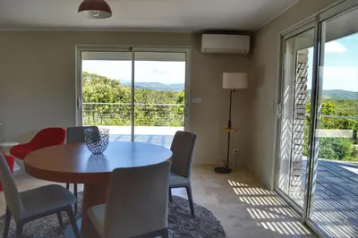 a dining room with a table and chairs and a balcony at Villa Serena - 10mn de la plage in Bonifacio