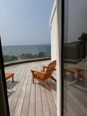 a wooden deck with a bench and tables on a balcony at Villa Solanella in Coti-Chiavari