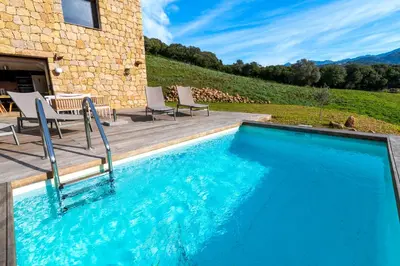 a swimming pool with chairs and a house at A Casetta Rossa Bergerie a 15 min du centre ville d Ajaccio et 15 min des plages de Porticcio in Ocana