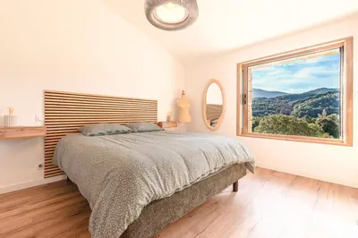 a bedroom with a bed and a large window at A Casetta Rossa Bergerie a 15 min du centre ville d Ajaccio et 15 min des plages de Porticcio in Ocana