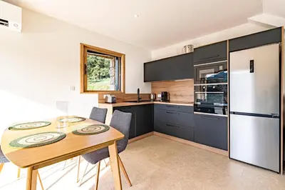 a kitchen with a wooden table and a refrigerator at A Casetta Rossa Bergerie a 15 min du centre ville d Ajaccio et 15 min des plages de Porticcio in Ocana