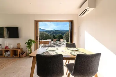 a dining room with a table and chairs and a large window at A Casetta Rossa Bergerie a 15 min du centre ville d Ajaccio et 15 min des plages de Porticcio in Ocana