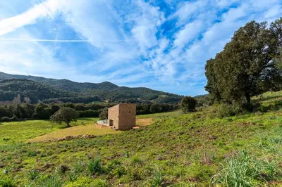 a building on a hill in a field at A Casetta Rossa Bergerie a 15 min du centre ville d Ajaccio et 15 min des plages de Porticcio in Ocana