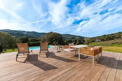 a deck with a table and chairs and a pool at A Casetta Rossa Bergerie a 15 min du centre ville d Ajaccio et 15 min des plages de Porticcio in Ocana