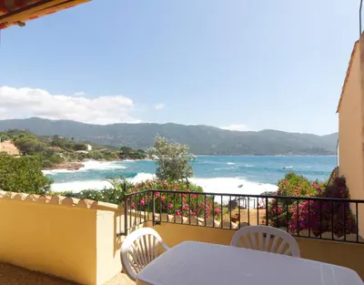 a balcony with a table and chairs and the ocean at Bel appartement 1 chambre pieds dans l'eau in Casaglione