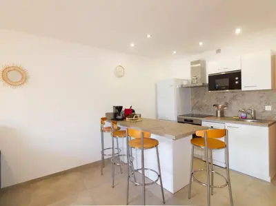 a kitchen with white cabinets and bar stools at Bel appartement 1 chambre pieds dans l'eau in Casaglione