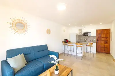 a living room with a blue couch and a kitchen at Bel appartement 1 chambre pieds dans l'eau in Casaglione