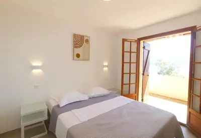 a bedroom with a bed and a sliding glass door at Bel appartement 1 chambre pieds dans l'eau in Casaglione