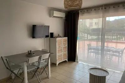 a dining room with a table and a balcony at 46m with terrace - residence with pool in Porto-Vecchio