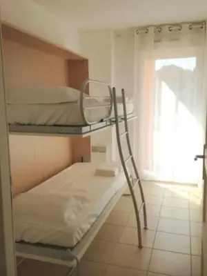 a bunk bed with a ladder in a room at 46m with terrace - residence with pool in Porto-Vecchio