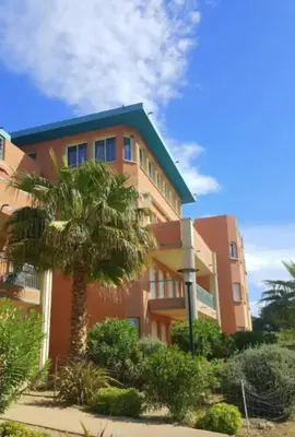 a building with a palm tree in front of it at 46m with terrace - residence with pool in Porto-Vecchio