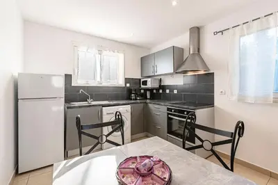 a kitchen with a white refrigerator and a table with chairs at Villa Maria Magdalena - Avec piscine in Sari Solenzara