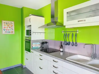 a kitchen with green walls and white cabinets and a sink at Apartment Agnaredda by Interhome in Porto-Vecchio