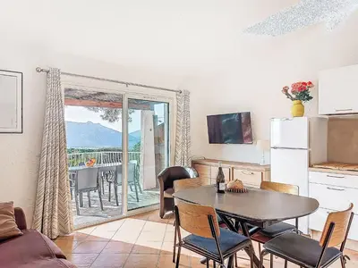 a living room with a table and a kitchen with a balcony at Apartment Marina Di Santa Giulia by Interhome in Porto-Vecchio