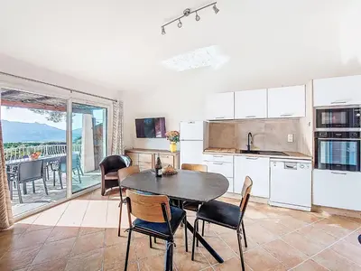 a kitchen with a table and chairs and a balcony at Apartment Marina Di Santa Giulia by Interhome in Porto-Vecchio