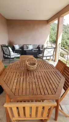 a wooden table sitting on a patio with chairs at Haut de Villa Superbe vue Piscine privee in Moltifao